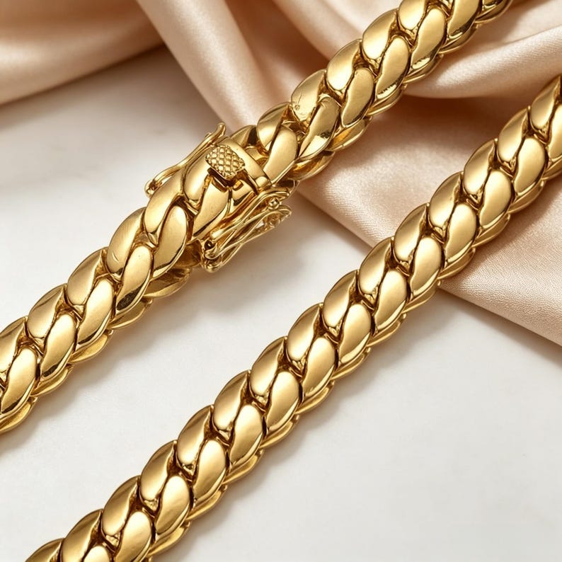 K&ouml;nnte beinhalten: Eine goldfarbene Halskette mit dickem, geflochtenem Design. Die Halskette verf&uuml;gt &uuml;ber einen sicheren Verschluss und eine polierte Oberfl&auml;che, die das Licht reflektiert. Der Schmuck wird auf einer weichen, neutralfarbenen Oberfl&auml;che pr&auml;sentiert.