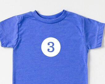 May include: A blue short-sleeved t-shirt with a white circle containing the number "3" in the center.