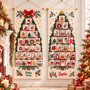 May include: Two vertical fabric advent calendars featuring embroidered Christmas tree designs with numbered pockets. The left calendar displays Miller Family, while the right calendar displays Sophie. Each pocket features unique holiday icons.