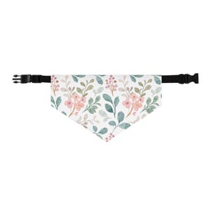 May include: A white pet bandana with a floral pattern featuring pink flowers, green leaves, and berries. The bandana has a black adjustable collar with a buckle closure. The overall design is a watercolor style.