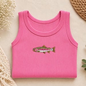 K&ouml;nnte beinhalten: Ein leuchtend pinkfarbenes geripptes Tanktop mit einer kleinen, detaillierten Stickerei einer Regenbogenforelle in der Mitte. Das Fischmotiv zeigt Gr&uuml;n-, Pink- und Wei&szlig;t&ouml;ne mit schwarzen Punkten und ist horizontal im Brustbereich platziert.
