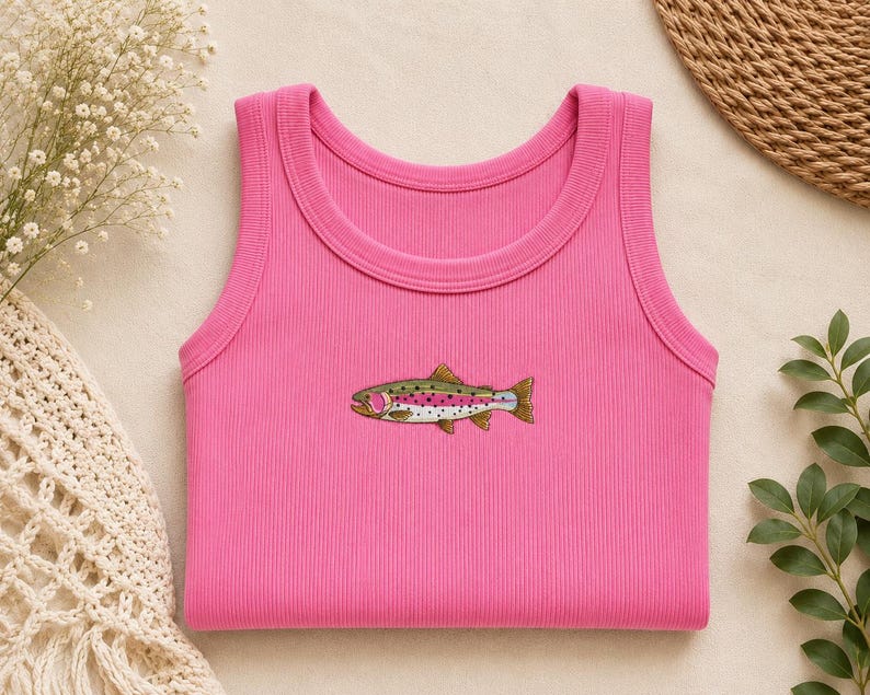 K&ouml;nnte beinhalten: Ein leuchtend pinkfarbenes geripptes Tanktop mit einer kleinen, detaillierten Stickerei einer Regenbogenforelle in der Mitte. Das Fischmotiv zeigt Gr&uuml;n-, Pink- und Wei&szlig;t&ouml;ne mit schwarzen Punkten und ist horizontal im Brustbereich platziert.