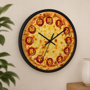 May include: A round wall clock with a pizza design. The clock face features a pizza with pepperoni slices marking the hours. The numbers are yellow, and the hands are black. The clock is set in a black frame.