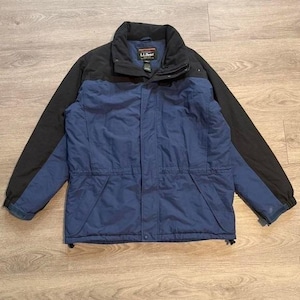 Puede incluir: Chaqueta L.L.Bean azul y negra. La chaqueta tiene cuello y mangas negras, con cuerpo azul. Tiene cierre de cremallera y múltiples bolsillos. El logotipo de L.L.Bean es visible en el cuello.