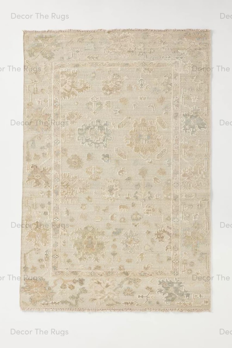 Puede incluir: Alfombra rectangular beige con un dise&ntilde;o floral desgastado y bordes deshilachados. La alfombra presenta un dise&ntilde;o central enmarcado por un borde, con tonos verdes y marrones apagados.