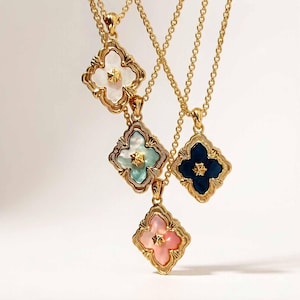 May include: Four gold-tone necklaces featuring quatrefoil-shaped pendants. Each pendant has a decorative gold border and a central star-shaped accent. The inlays are white, light blue, dark blue, and pink, suspended on delicate gold-tone chains.