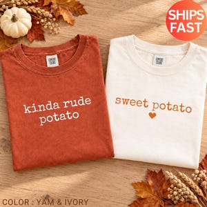 Könnte beinhalten: Ein rostfarbenes T-Shirt mit dem weißen Text "kinda rude potato" und ein elfenbeinfarbenes T-Shirt mit dem orangefarbenen Text "sweet potato" und einem kleinen Herzsymbol. Beide T-Shirts haben einen Rundhalsausschnitt und ein Comfort Colors Etikett.