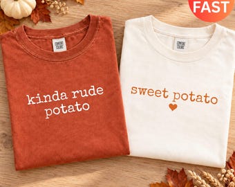 Könnte beinhalten: Ein rostfarbenes T-Shirt mit dem weißen Text "kinda rude potato" und ein elfenbeinfarbenes T-Shirt mit dem orangefarbenen Text "sweet potato" und einem kleinen Herzsymbol. Beide T-Shirts haben einen Rundhalsausschnitt und ein Comfort Colors Etikett.