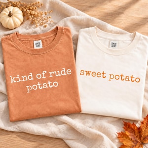 May include: Two crew neck t-shirts with Comfort Colors labels. One shirt is burnt orange with the white text "kind of rude potato" and the other is off-white with the orange text "sweet potato" printed in a simple sans-serif font.