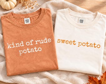 Könnte beinhalten: Zwei T-Shirts mit Rundhalsausschnitt und Comfort Colors-Etiketten. Das linke Shirt ist rostorange mit weißem Text kind of rude potato. Das rechte Shirt ist cremeweiß mit orangefarbenem Text sweet potato. Beide Shirts haben kurze Ärmel.