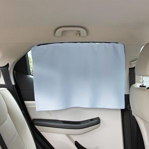 May include: A light blue rectangular car window shade installed on the interior side window of a vehicle. The shade is made of a solid, opaque fabric that covers the glass, positioned between the light-colored headrests and the door panel.