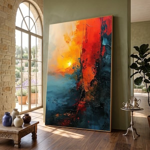 May include: Large abstract painting with a vibrant colour palette. The artwork features a blend of orange, red, blue, and black hues, creating a dynamic and expressive composition. The painting is displayed in a well-lit room, leaning against a wall.