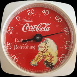 May include: A round Coca-Cola thermometer with a white frame and a red face. The dial features the text Drink Coca-Cola, Delicious and Refreshing, and a graphic of a person holding a bottle cap. It displays temperature in Fahrenheit and Celsius.