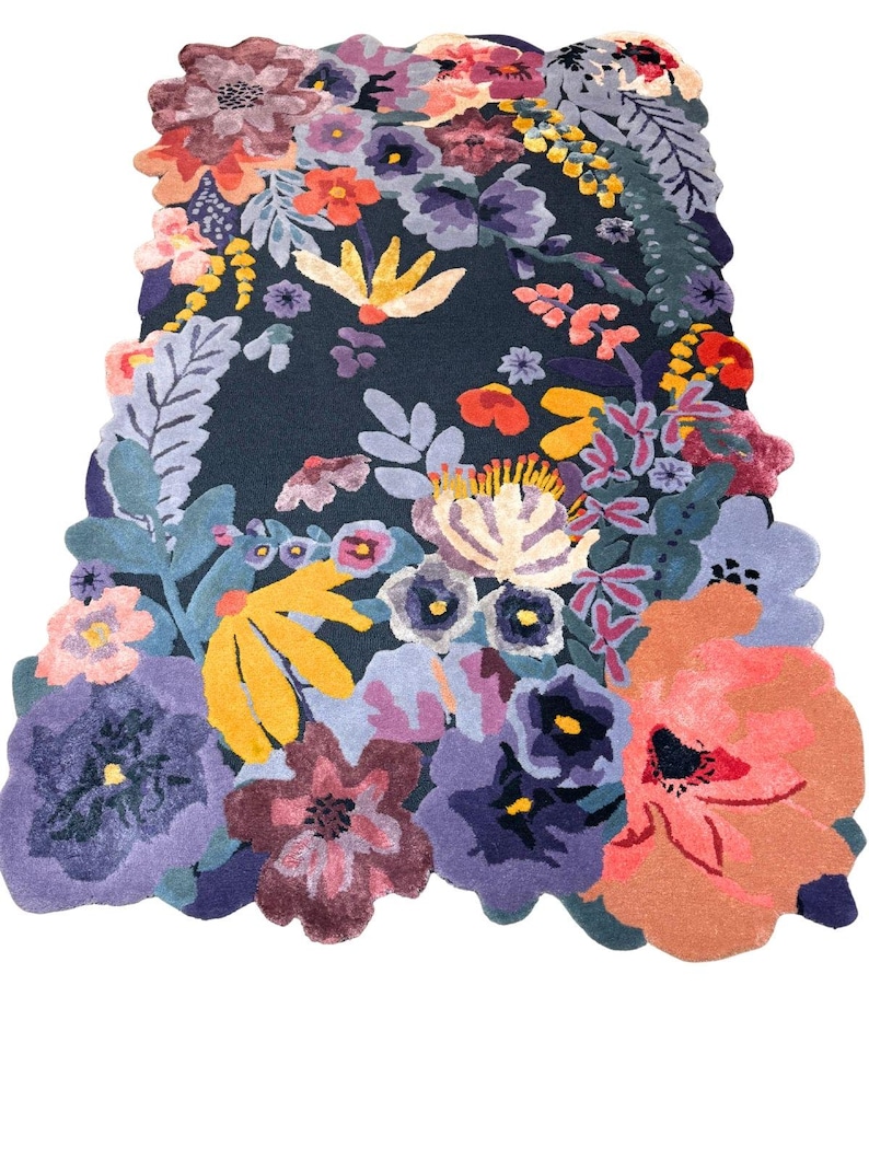 May include: A colourful floral rug featuring a dark blue backdrop and a vibrant arrangement of flowers in purple, orange, yellow, and pink. The rug has an unusual, irregular shape, with the flowers extending beyond the edges.