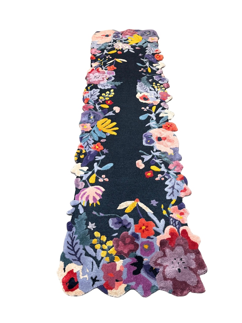 Puede incluir: Una alfombra de pasillo azul oscuro con un dise&ntilde;o floral. La alfombra presenta un campo central azul oscuro bordeado por una vibrante variedad de flores coloridas en tonos de rojo, amarillo, morado y rosa. Los bordes de la alfombra siguen el patr&oacute;n floral.