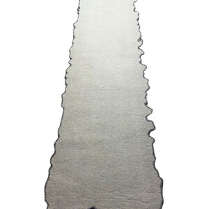 Puede incluir: Una alfombra rectangular gris claro con un borde &uacute;nico e irregular. La alfombra tiene una superficie texturizada y un borde gris oscuro que sigue la forma irregular. Dise&ntilde;ada para uso en interiores.