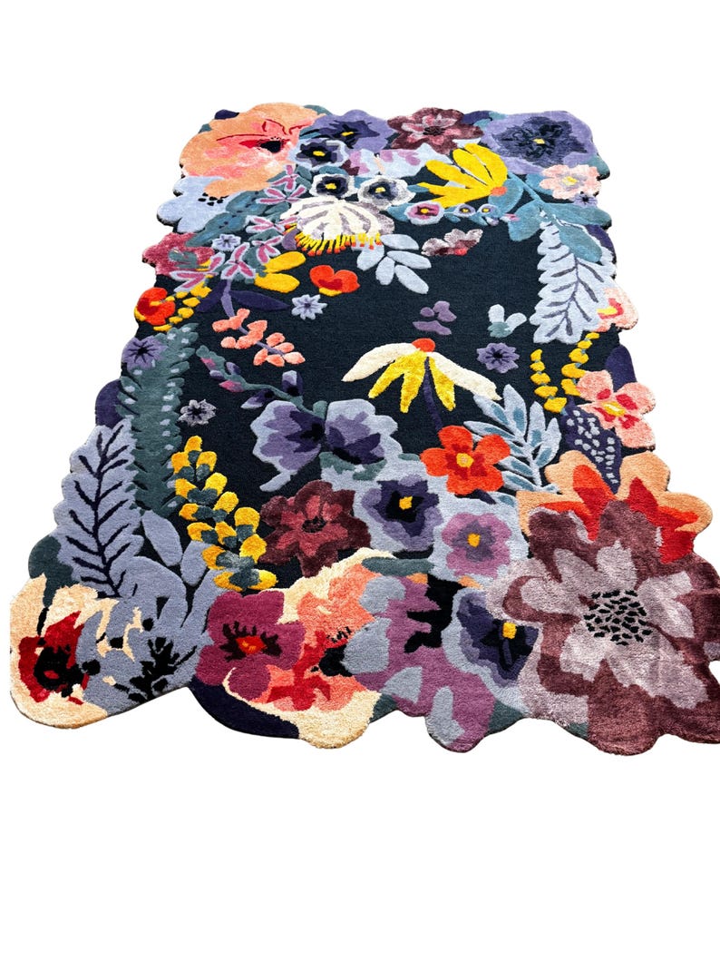 May include: A colourful floral rug featuring a dark background and a variety of flowers in shades of red, yellow, purple, and blue. The rug has an irregular shape and a textured appearance.