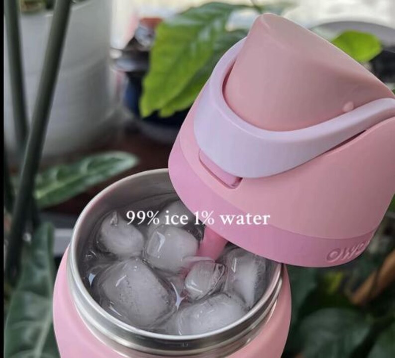 Może przedstawiać: R&oacute;żowa, izolowana butelka na wodę z jasnor&oacute;żową pokrywką, wypełniona kostkami lodu. Na butelce wydrukowano tekst "99% ice 1% water". Pokrywka jest otwarta, odsłaniając wnętrze butelki.