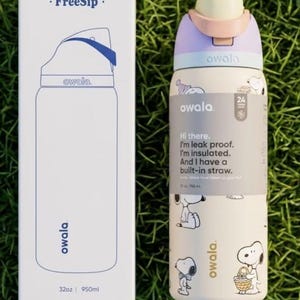 K&ouml;nnte beinhalten: Eine wei&szlig;e und lavendelfarbene Owala FreeSip Wasserflasche mit Snoopy-Design und eingebautem Strohhalm. Die Flasche fasst 950 ml und tr&auml;gt den Text "Hi there. I'm leak proof. I'm insulated."