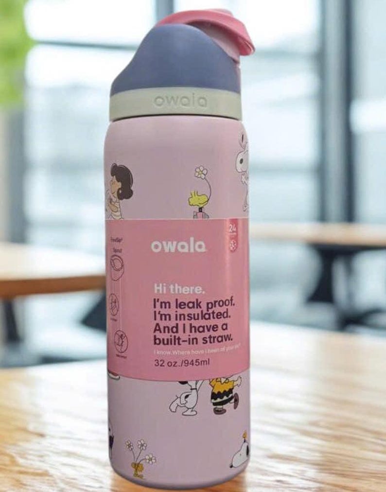 Może przedstawiać: R&oacute;żowa i fioletowa butelka na wodę Owala z klapką. Butelka przedstawia postacie z kresk&oacute;wek i tekst "Hi there. I'm leak proof. I'm insulated. And I have a built-in straw." Mieści 945 ml.