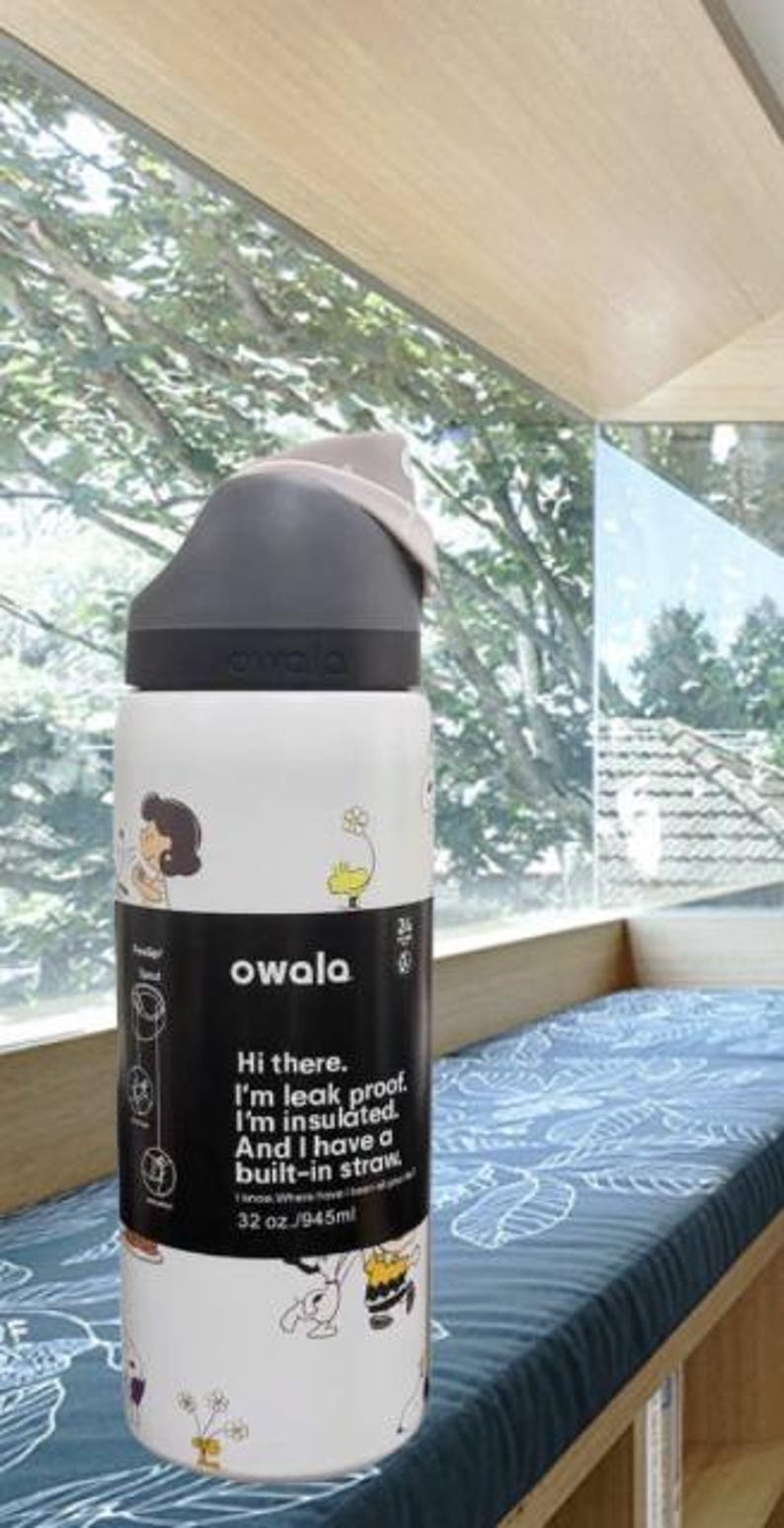 K&ouml;nnte beinhalten: Owala Isolierflasche in Wei&szlig; und Schwarz mit eingebautem Strohhalm. Die Flasche hat einen schwarzen Deckel und einen wei&szlig;en K&ouml;rper mit Cartoon-Illustrationen und dem Text "Hi there. I'm leak proof. I'm insulated. And I have a built-in straw. 945ml."