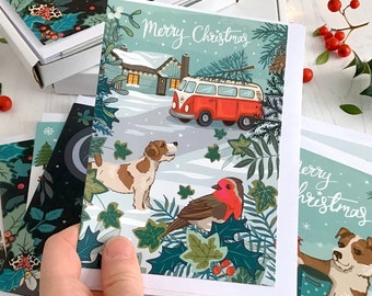 Merry Christmas card featuring dog, camper van and snow topped lodge