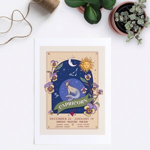 May include: A vintage-style illustration of the Capricorn zodiac sign. The illustration features a sea-goat, a crescent moon, a sun, and a constellation of stars against a blue background. The illustration is surrounded by purple and yellow pansies. The text "Capricorn" is written in a decorative font below the illustration. The text "December 22 - January 19" is written below the text "Capricorn". The text "Ambitious, Disciplined, Practical" is written below the dates. The text "Element: Earth, Gemstone: Garnet, Ruler: Saturn, Flower: Pansy" is written below the personality traits.