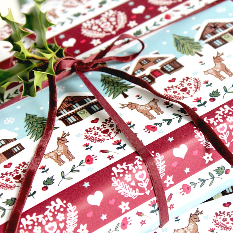May include: Red and white striped wrapping paper with a winter scene featuring houses, trees, deer, and hearts. The paper is tied with a burgundy velvet ribbon.