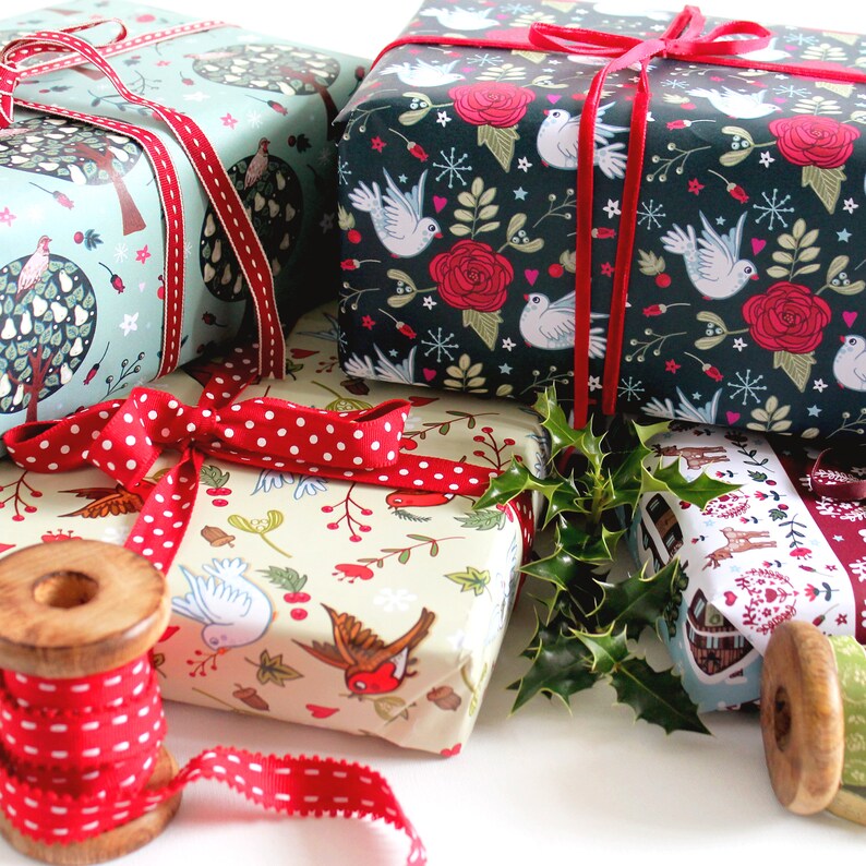 May include: Three different patterned gift wrapping papers with red ribbon and holly sprigs. The papers feature a variety of designs including birds, trees, and flowers.