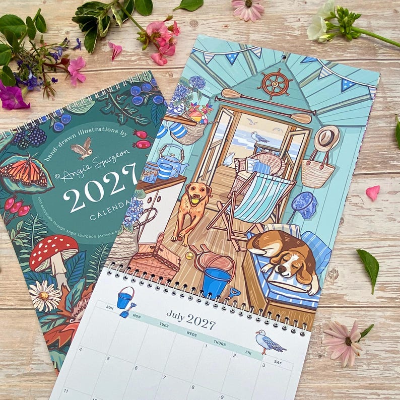 May include: A 2027 wall calendar featuring hand-drawn illustrations by Angie Spurgeon. The cover displays botanical art with a butterfly and mushroom, while the open page shows a beach hut scene with two dogs, a deck chair, and a July 2027 grid.