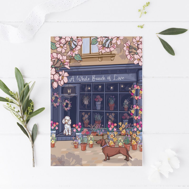 Valentine's Day Card or Anniversary Card featuring a poodle and dachshund by a florist shop. Text on card reads 'A Whole Bunch of Love'. Pink blossom and spring flowers also feature on the card.