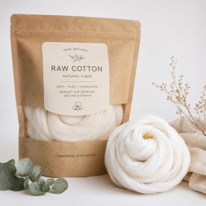 May include: A brown paper pouch containing white raw cotton fiber with a label reading 100% NATURAL RAW COTTON NATURAL FIBER SOFT PURE UNBLEACHED PERFECT FOR SPINNING FELTING & CRAFTS HANDMADE WITH NATURE. A coiled bundle of white cotton sits beside it.