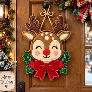 May include: A decorative reindeer wall hanging featuring a brown plush face with embroidered details, a bright red nose, and large antlers. The reindeer is adorned with a large red fabric bow and green holly leaves, suspended by a gold cord.