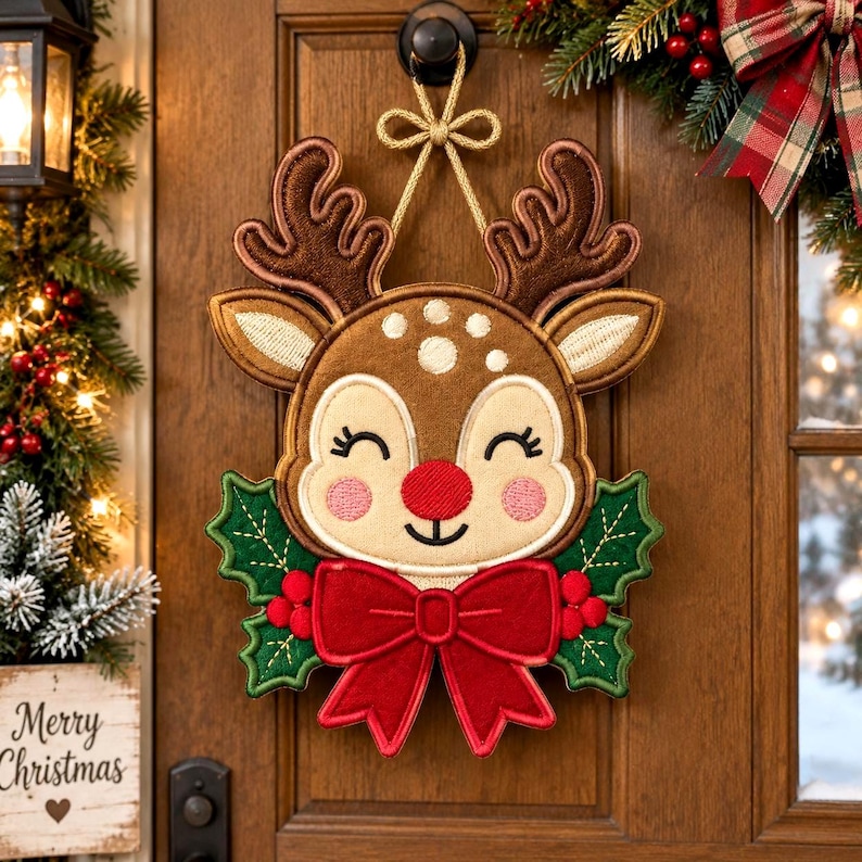 May include: A decorative reindeer wall hanging featuring a brown plush face with embroidered details, a bright red nose, and large antlers. The reindeer is adorned with a large red fabric bow and green holly leaves, suspended by a gold cord.