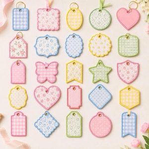 May include: A collection of twenty-five fabric gift tags in various shapes including hearts, stars, butterflies, and rectangles. Each tag features distinct patterns such as gingham, floral, and polka dots in pastel colors with metal rings for hanging.