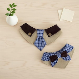 May include: Two pet bandanas designed to look like shirts. One has a blue plaid tie, the other a blue plaid bow tie. Both have a tan collar and brown accents. A small white vase with a green plant is in the background.