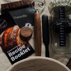 Peut inclure: Un kit de fabrication de pain au levain comprenant un grattoir &agrave; p&acirc;te en m&eacute;tal marqu&eacute; Gustella avec manche en bois, un fouet &agrave; p&acirc;te en fil m&eacute;tallique, une lame &agrave; pain en bois, une spatule noire, un bocal en verre avec bande de temp&eacute;rature et un livret de recettes Gustelo Sourdough.