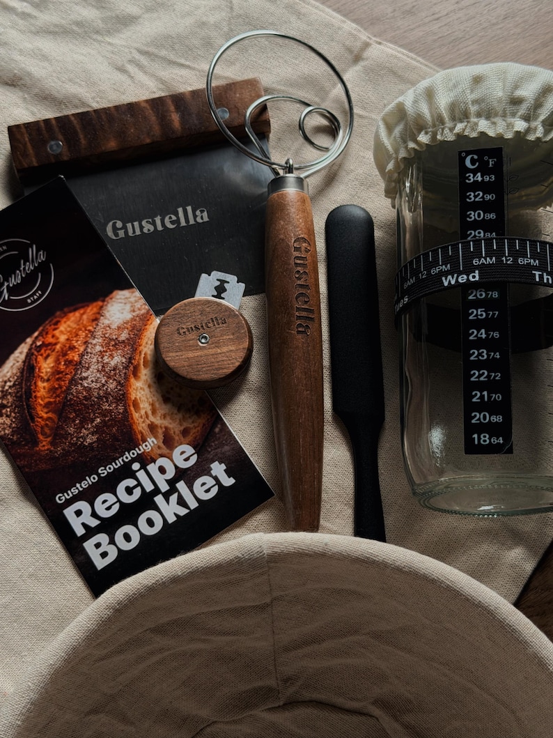 Peut inclure: Un kit de fabrication de pain au levain comprenant un grattoir &agrave; p&acirc;te en m&eacute;tal marqu&eacute; Gustella avec manche en bois, un fouet &agrave; p&acirc;te en fil m&eacute;tallique, une lame &agrave; pain en bois, une spatule noire, un bocal en verre avec bande de temp&eacute;rature et un livret de recettes Gustelo Sourdough.