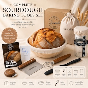 May include: A complete sourdough baking tools set by Gustella including a round proofing basket with a loaf of bread, a metal dough scraper with a wooden handle, a dough whisk, a glass starter jar with a cloth cover, and a recipe booklet.