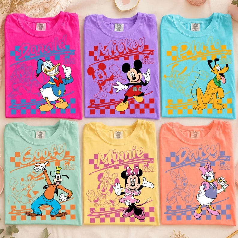 May include: Six crew neck t-shirts in bright colors, each featuring a Disney character: Donald Duck on pink, Mickey Mouse on purple, Pluto on light blue, Goofy on mint green, Minnie Mouse on yellow, and Daisy Duck on peach, all with 1928 text.