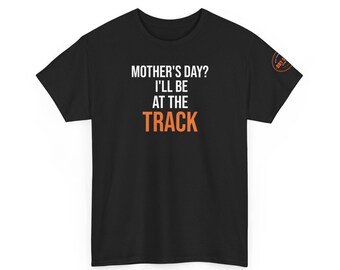 May include: Black t-shirt with the text "MOTHER'S DAY? I'LL BE AT THE TRACK" in white and orange. A small circular logo is on the right sleeve. The shirt is a casual wear item.