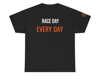 May include: A black short-sleeve t-shirt featuring the text RACE DAY in white letters and EVERY DAY in orange letters on the front. A small circular orange and black logo is visible on the left sleeve. The shirt has a crew neckline and a standard fit.