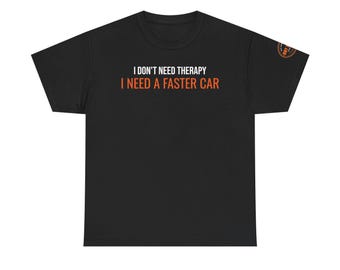 May include: A black short-sleeved t-shirt featuring the white text I DON'T NEED THERAPY and the orange text I NEED A FASTER CAR centered on the chest. A small circular orange and black logo is visible on the upper right sleeve of the garment.