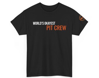 May include: A black short-sleeve t-shirt featuring the white text "WORLD'S OKAYEST" above the orange text "PIT CREW" on the chest. A small circular orange and black logo is printed on the right sleeve, containing the text "DRY BLEND".