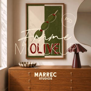 Puede incluir: Un cuadro enmarcado con un diseño de aceitunas verdes y rojas sobre un fondo blanco y verde. La palabra "OLIVE" está en rojo. La obra de arte se exhibe sobre una cómoda de madera, con una lámpara y un cuenco decorativo.