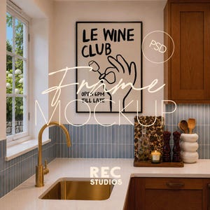 Peut inclure: Une affiche encadrée représentant un dessin au trait noir d'une main tenant un verre de vin avec le texte LE WINE CLUB OPEN 6PM TILL LATE. L'affiche est exposée dans une cuisine avec un robinet doré, un évier blanc et une crédence bleue.