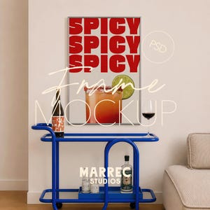 Könnte beinhalten: Ein gerahmter Kunstdruck mit dem Wort "SPICY" in Rot. Ein blauer Servierwagen hält eine Weinflasche, einen Cocktail, ein Glas Rotwein und Spirituosenflaschen. Der Wagen steht vor einer weißen Wand.