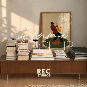 May include: A framed vertical print featuring an illustration of a person in a hat playing a yellow saxophone while standing on a green vinyl record. The artwork is displayed on a wooden sideboard alongside stacks of books and a wine glass.