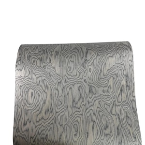 May include: A sheet of flexible material featuring a high-contrast wood grain pattern in shades of light gray, charcoal, and white. The design consists of swirling, organic lines that mimic the natural growth rings found in timber.