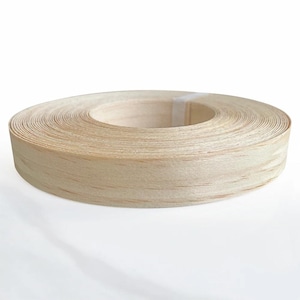 May include: A continuous roll of light-colored wood veneer edge banding featuring a natural grain pattern. The thin, flexible strip is coiled into a circular shape with a smooth, flat surface and a visible light-colored adhesive strip securing the end.
